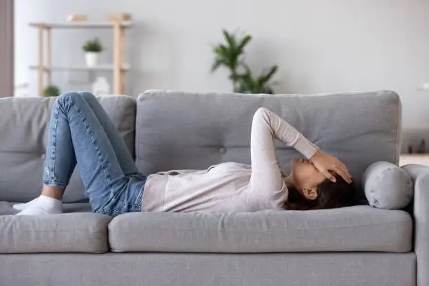 Photo of Full length young woman lying on couch suffers from heartache