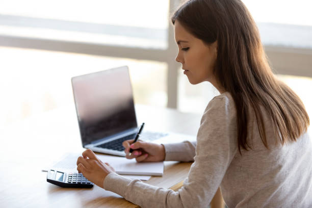 istock Side rear view young female sitting at table calculating money 1150540171