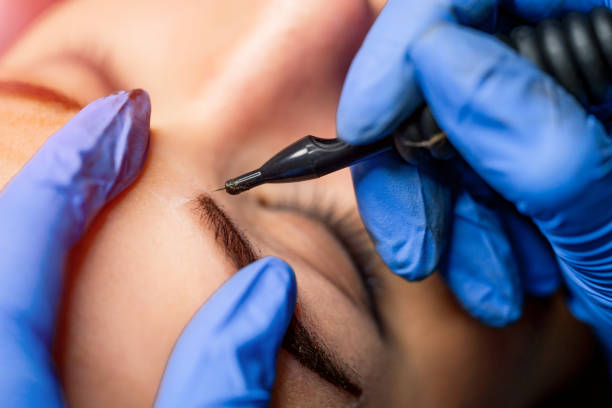 istock Cosmetician working, making permanent makeup in beauty salon. Beautician making permanent makeup of eyebrows. 1150544764