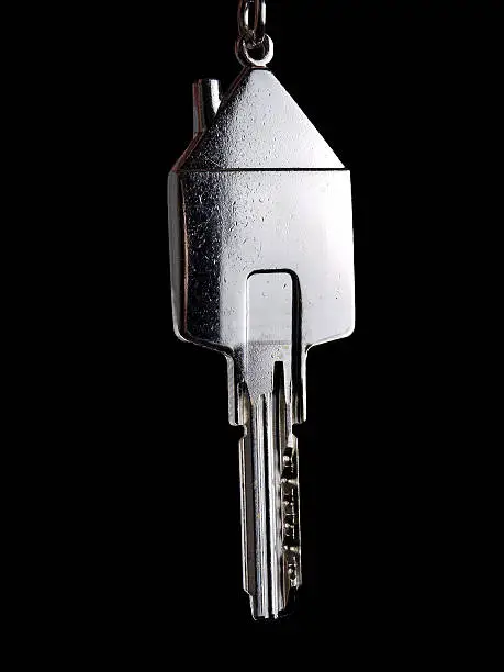 Key as a symbol of owning your own home isolated on black background.