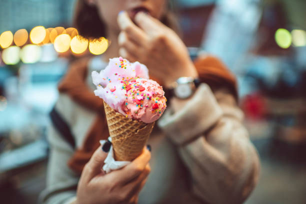 Teen girl with pink eating ice-cream outdoors in summer Happy teenager eating ice-cream in the city in the evening cone shape stock pictures, royalty-free photos & images