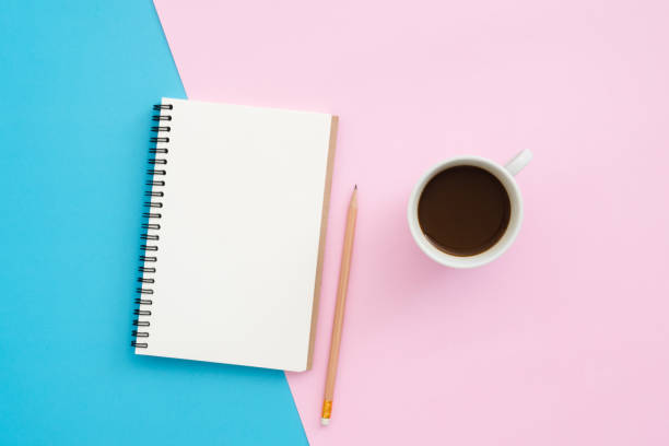 istock Creative flat lay photo of workspace desk. Top view office desk with pencil, notebook and coffee cup on blue pink color background. Top view with copy space, flat lay photography. 1150549335