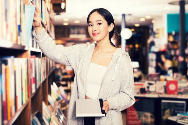 istock Girl choosing books on library shelves 1150554578