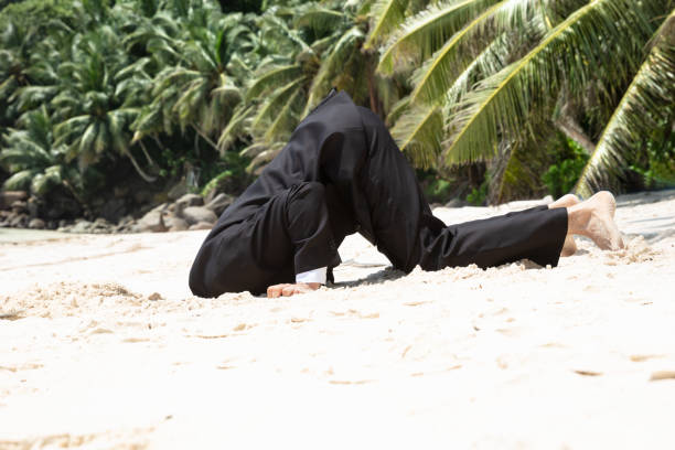 Unsuccessful Businessman Burying His Head In The Sand Side View Of Unsuccessful Businessman Burying His Head In The Sand At Beach burying stock pictures, royalty-free photos & images