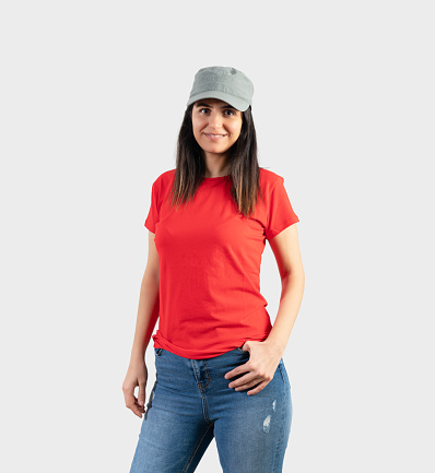 Young girl wearing blank red t-shirt, cap  and blue jeans. Grey wall background .