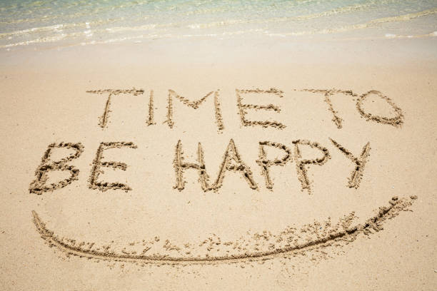 Close-up Of Time To Be Happy Text And Smile Written On Sand At Beach