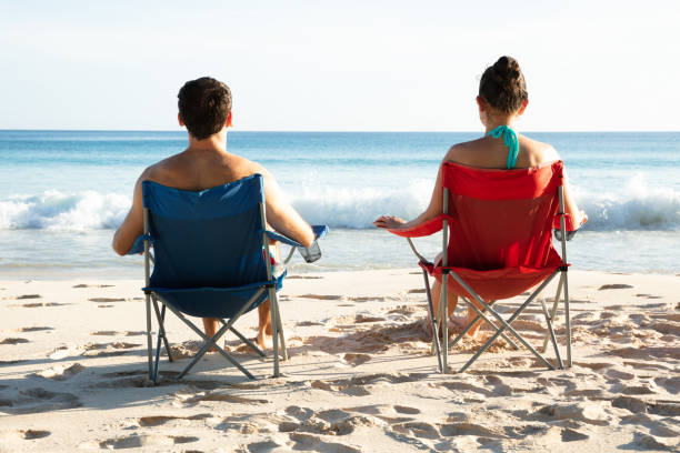 istock Young Couple Sitting On Beach Looking At Sea 1150556687