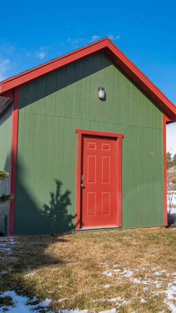 istock Clear Vertical Small storage shed on grassy terrain with trees and powdery snow 1150556789