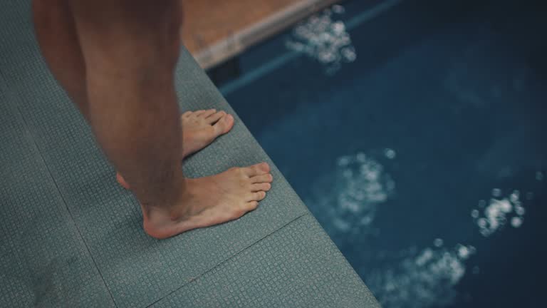 Athlete diving from platform into blue pool