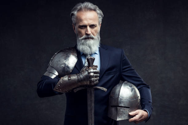 Classy dressed senior businessman with knight sword Portrait of a handsome self-confident well dressed businessman holding knight sword sword photos stock pictures, royalty-free photos & images