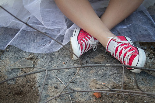 A Girl In A White Airy Layered Dress And Red Sneakers Crossed Her Legs  Stock Photo - Download Image Now - iStock