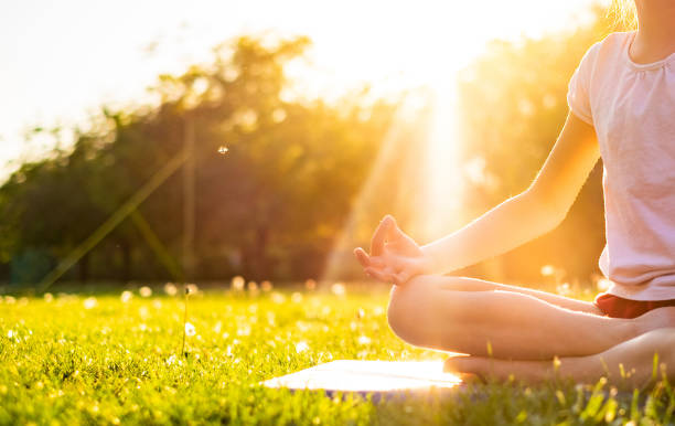 Unrecognizable girl in yoga pose Unrecognizable girl meditate sitting on grass at sunset mindfulness children stock pictures, royalty-free photos & images