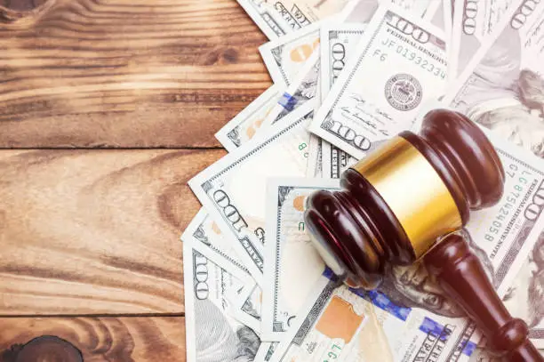 Gavel with money on wooden background. Space for text. Toned image.