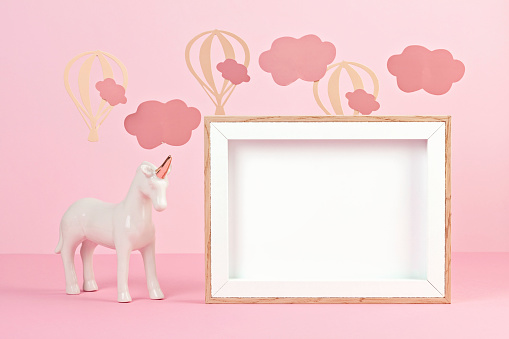 Cute white unicorn over the pink pastel background with clouds and baloons. Baby shower, girl birthday concept