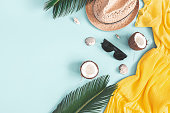 Summer composition. Tropical leaves, dress, hat, coconut on blue background. Summer concept. Flat lay, top view, copy space