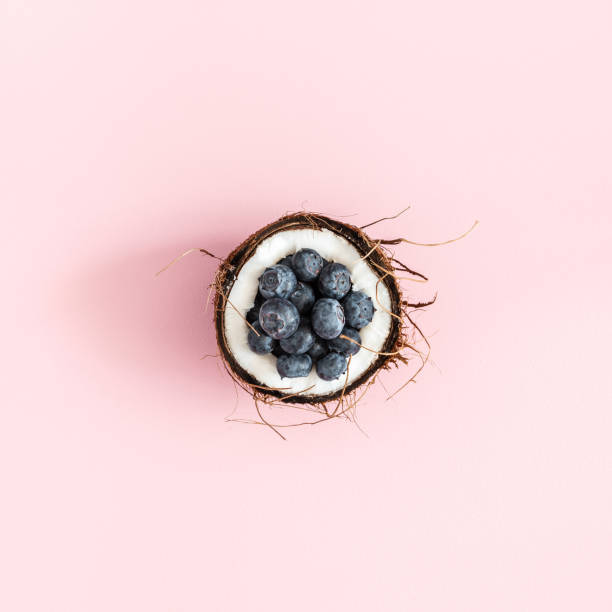 Coconut and blueberry on pink background. Flat lay, top view, square