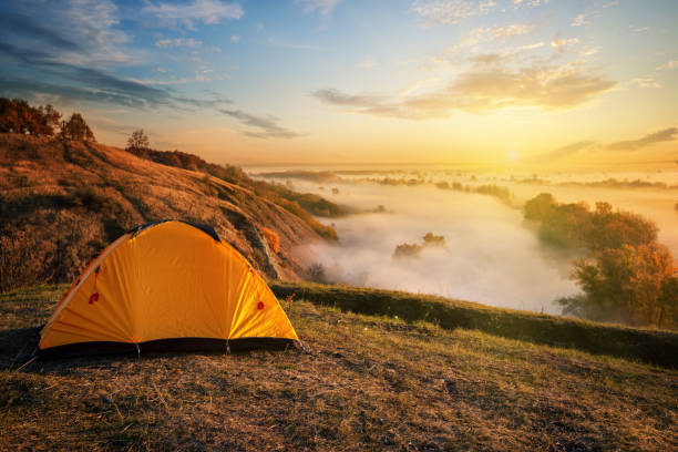istock Orange tent in canyon over misty river at sunset 1150567454