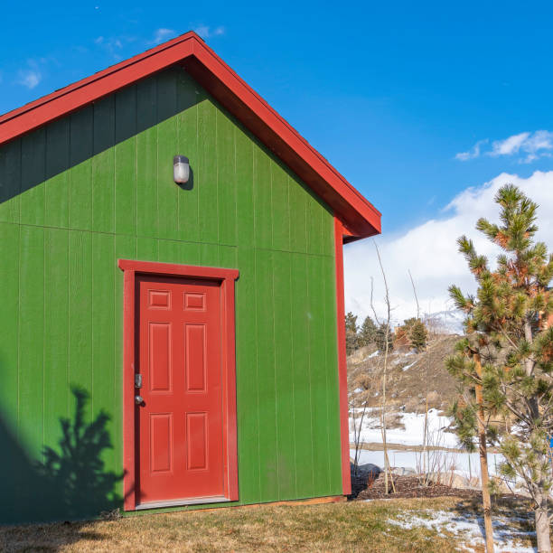 istock Square Small storage shed on grassy terrain with trees and powdery snow 1150568841