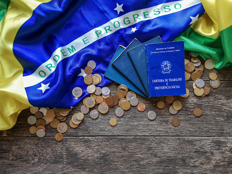 Brazilian flag with Brazilian document work and social security and coins with wooden background