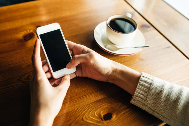 istock Woman using smartphone on wooden table in cafe 1150570352