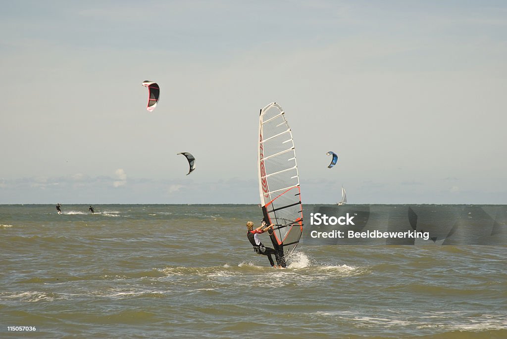 windsurfer windsurfer with kite surfers in the background making his way through the surf on the dutch coast Activity Stock Photo