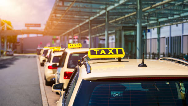 乗客を待っているタクシーキャブ。タクシーの車に黄色のタクシーサイン。空港ゲート前で乗客が到着するのを待っているタクシー車。タクシーは、乗客を待っている空港ターミナルに立っ� - タクシー ストックフォトと画像