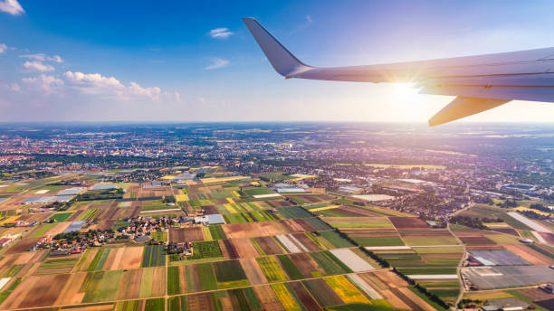 istock Airplane windows view above the earth on landmark down. View from an airplane window over a wing flying high above farmlands and fields. View from window of plane airplane flying. 1150571630