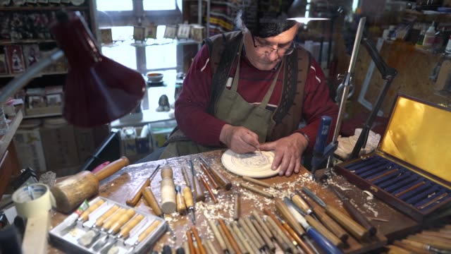 Senior artisan working in his studio on decorative wood object