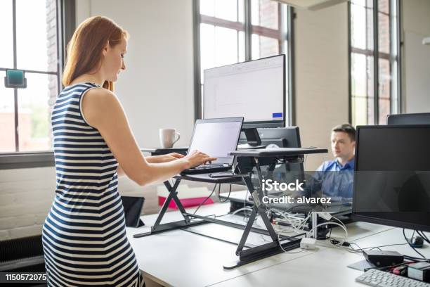 Businesswoman Working At Ergonomic Standing Desk Stock Photo - Download Image Now - Standing Desk, Standing, Ergonomics