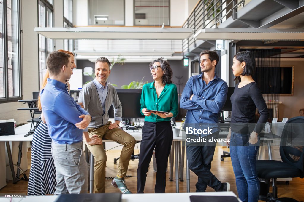 Happy business team having a standing meeting in office Group of multi-ethnic business people having a meeting in office. Businessmen and businesswoman having a standing meeting in modern office. Teamwork Stock Photo