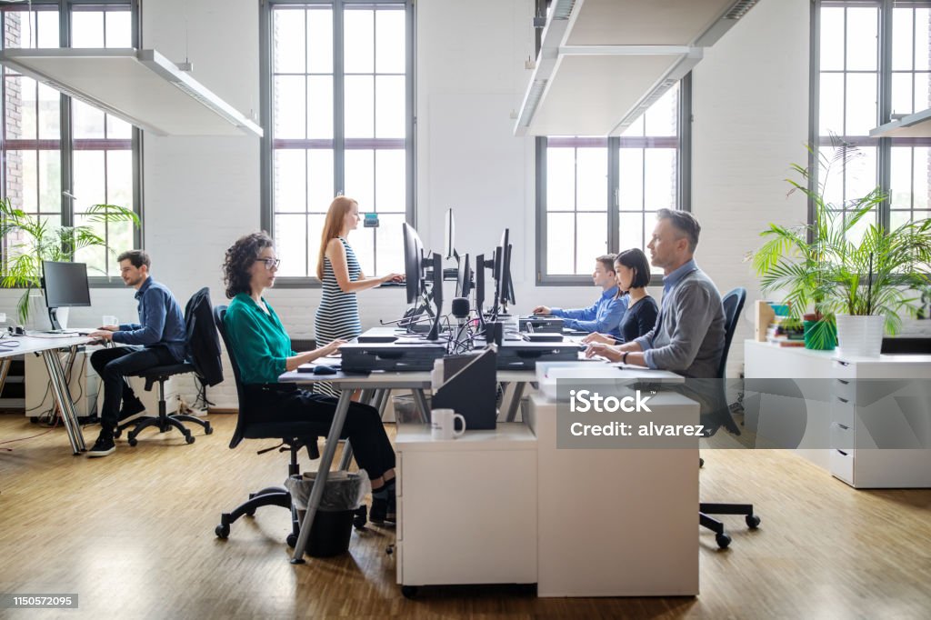 Business people working at a modern office Business people at their desks in a busy, open plan office. Startup business people working at a modern office. Office Stock Photo