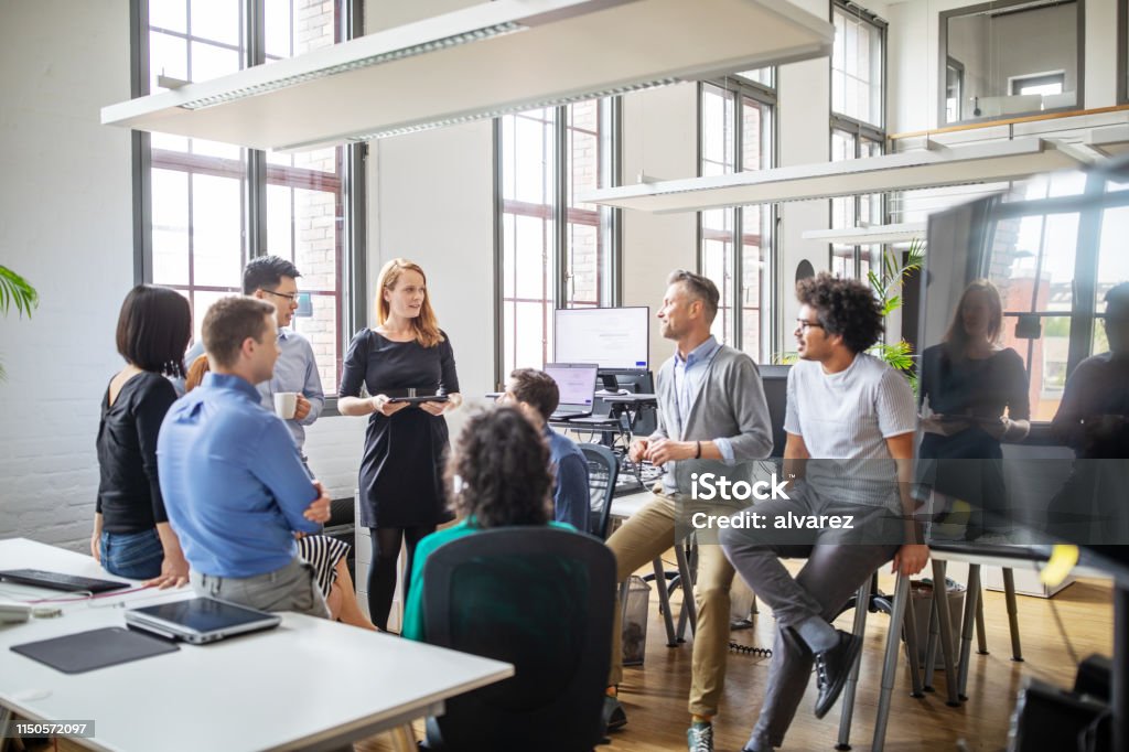 Group of professionals discussing new business plan Multi-ethnic business people sharing ideas in a modern office. Group of professionals discussing new business plan in meeting. Teamwork Stock Photo