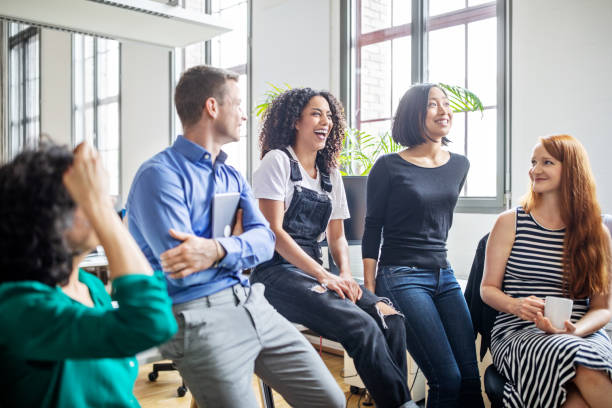 Professionals laughing in a meeting Cheerful multi-ethnic business colleagues in meeting. Male and female professionals laughing during a meeting. business caucasian meeting men stock pictures, royalty-free photos & images