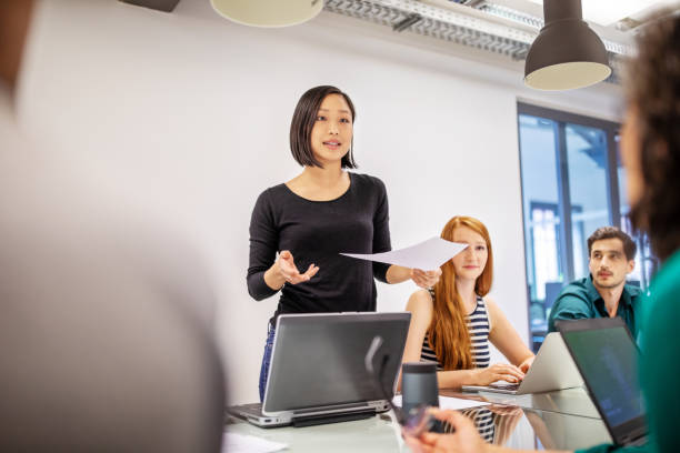 Confident female professional discussing with colleagues Confident female professional discussing in board room. Group of business colleagues planning together in meeting. presentation stock pictures, royalty-free photos & images