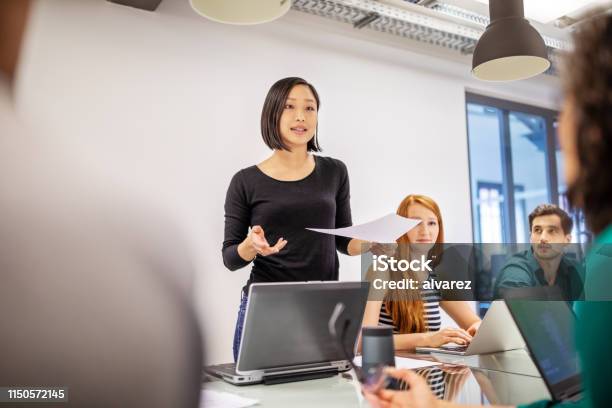 Confident Female Professional Discussing With Colleagues Stock Photo - Download Image Now