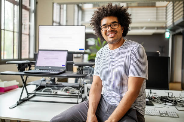 책상에 앉아 웃는 젊은 전문가의 초상화 - business person sitting looking at camera corporate business 뉴스 사진 이미지