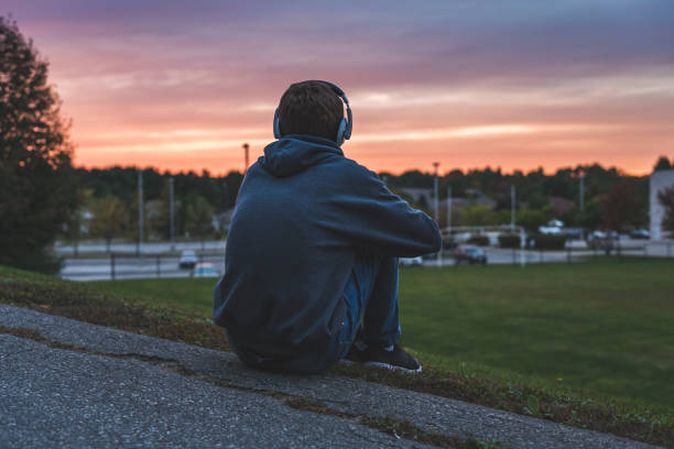 подросток слушает музыку и наблюдает закат. - romantic sky audio стоковые фото и �изображения
