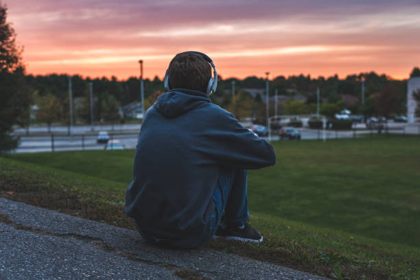 adolescente escuchando música y viendo la puesta de sol. - romantic sky audio fotografías e imágenes de stock