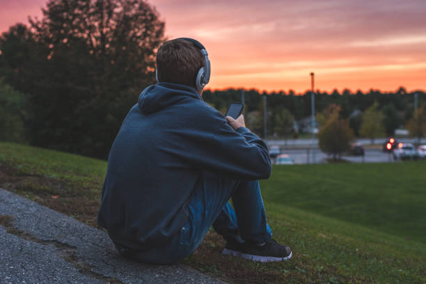 adolescente escuchando música y viendo la puesta de sol. - romantic sky audio fotografías e imágenes de stock