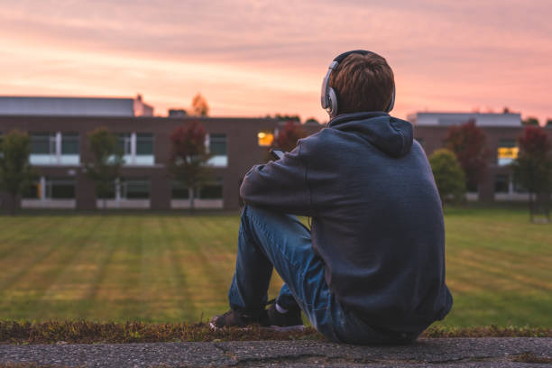 adolescente escuchando música y viendo la puesta de sol. - romantic sky audio fotografías e imágenes de stock