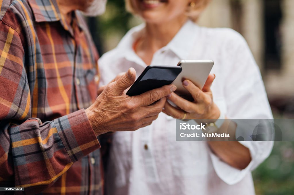 Charge Sharing Senior couple using smartphones Active Seniors Stock Photo