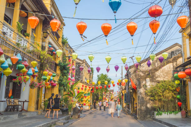 Colourful architecture and lanterns along streets of Hoi An Ancient Town during the day Hoi An, Vietnam - 24th March 2017:  Colourful architecture and lanterns along streets of Hoi An Ancient Town during the day. People can be seen. hoi an stock pictures, royalty-free photos & images