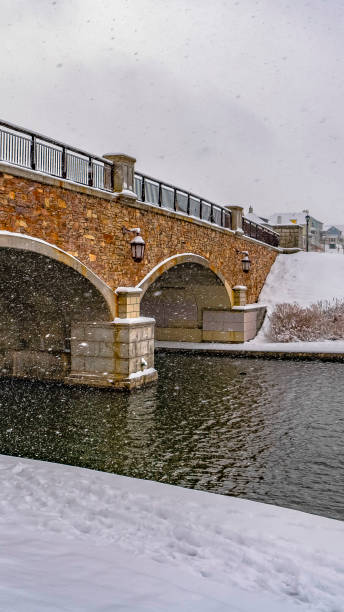istock Vertical Stone arched bridge with lamps over a lake during winter in Daybreak Utah 1150579061