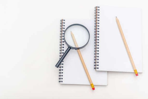 istock Blank sheet of notebook with a spiral and pen on a white background. Magnifying glass. Copy space 1150580182