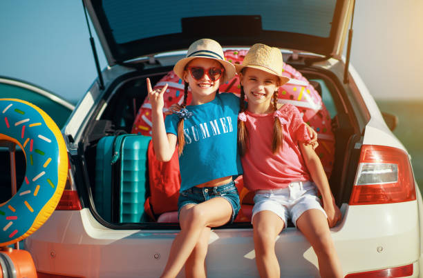 glückliche kinder mädchen zwillingsschwestern auf der autofahrt zur sommerreise - people child twin smiling stock-fotos und bilder