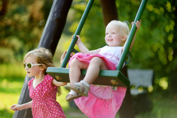 istock Two little sisters having fun on a swing 1150584078