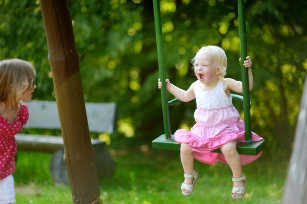 istock Two little sisters having fun on a swing 1150584103