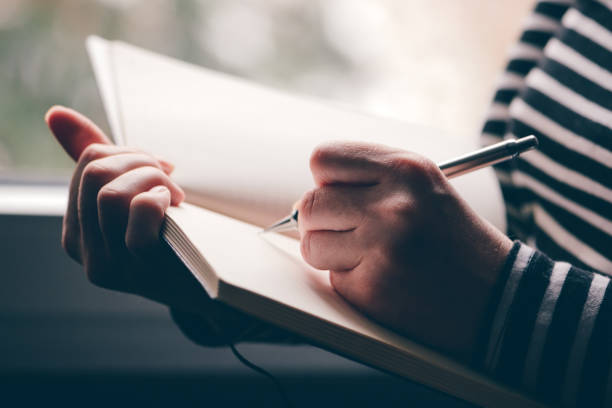 Left-handed woman writing diary, close up