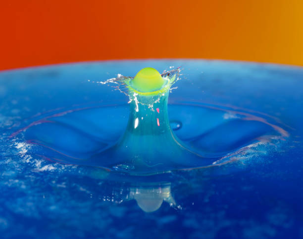 istock Droplet photography: a yellow drop falling into the blue water 1150590402