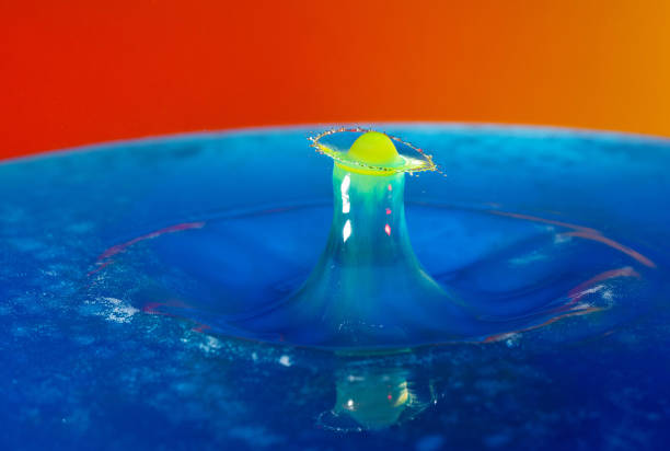istock Droplet photography: a yellow drop falling into the blue water 1150590404